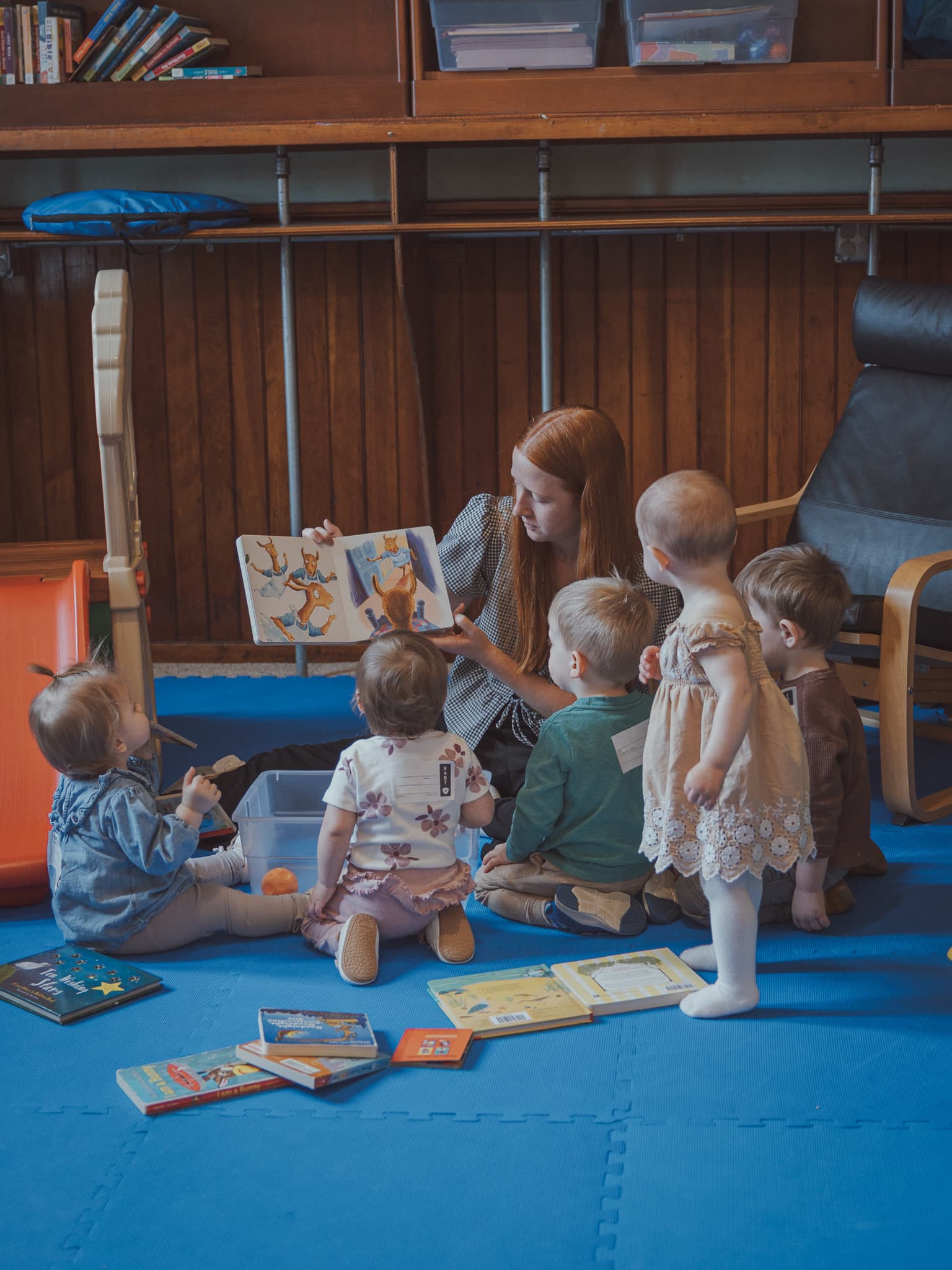 A River City Kids volunteer reading to children gathered for story time